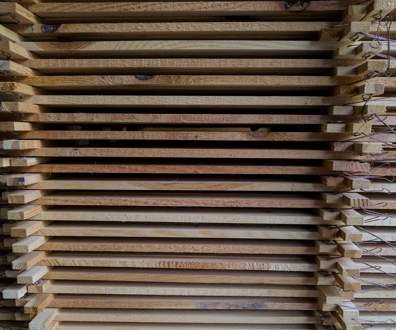 Pile de planches de bois empilées en couches régulières, vues par la tranche