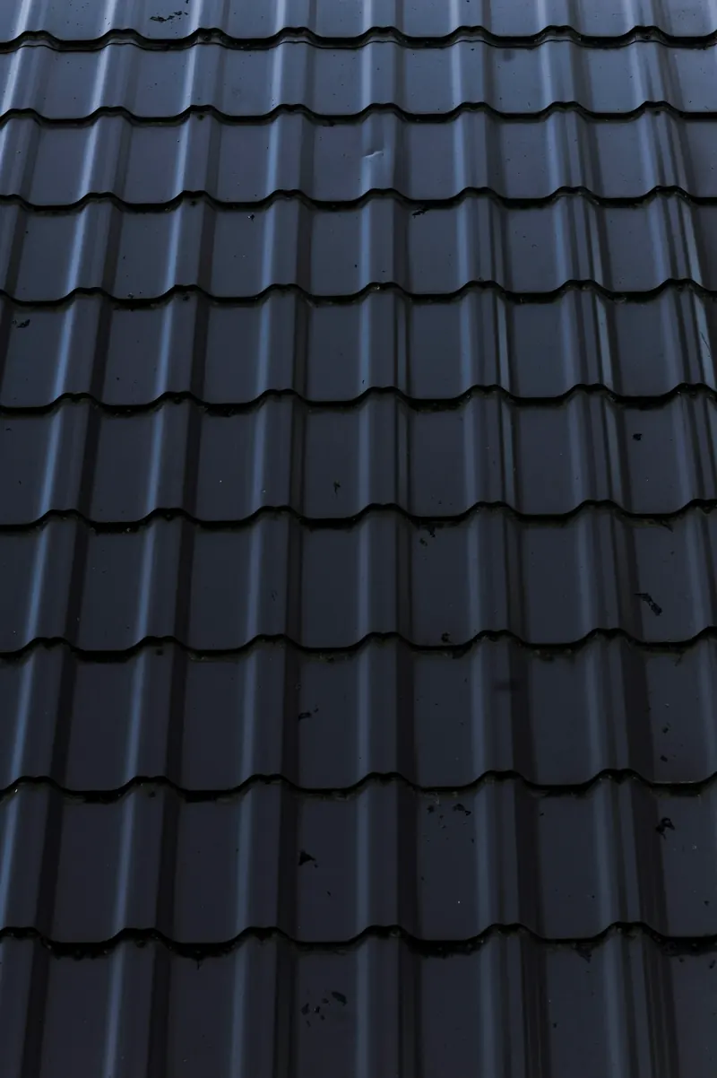 Gros plan sur une couverture métallique gris bleuté, aux rangs de tuiles régulières