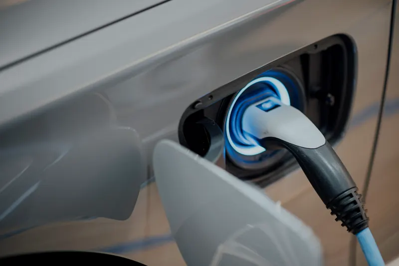Prise de recharge branchée sur la trappe d'un véhicule électrique, anneau lumineux bleu autour de la prise