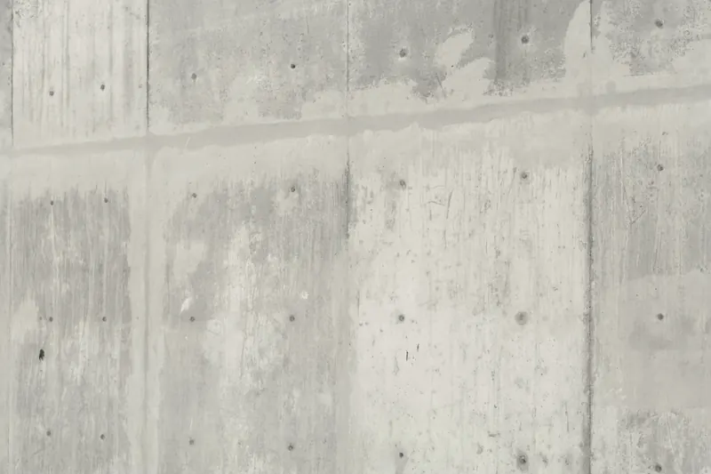 Mur de béton banché gris clair, marqué des trous de banche et des joints de coffrage