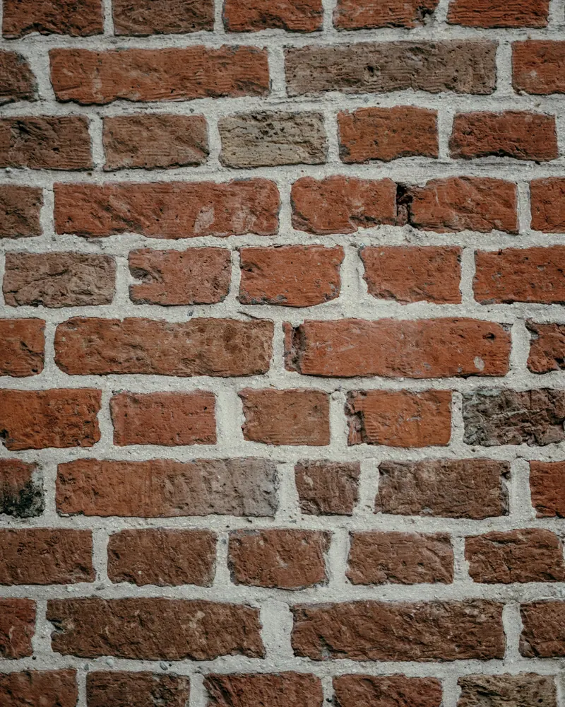 Mur de briques rouges vieillies aux joints de mortier clair, montées à joints décalés