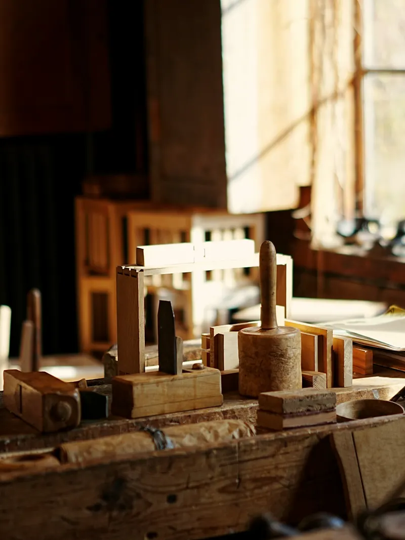 Établi d'atelier en lumière de fenêtre, avec un cadre assemblé à queues d'aronde, un maillet en bois et des rabots