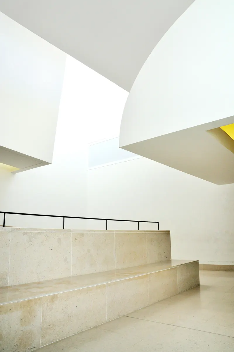 Murs et volumes blancs aux surfaces lisses au-dessus de marches en pierre claire