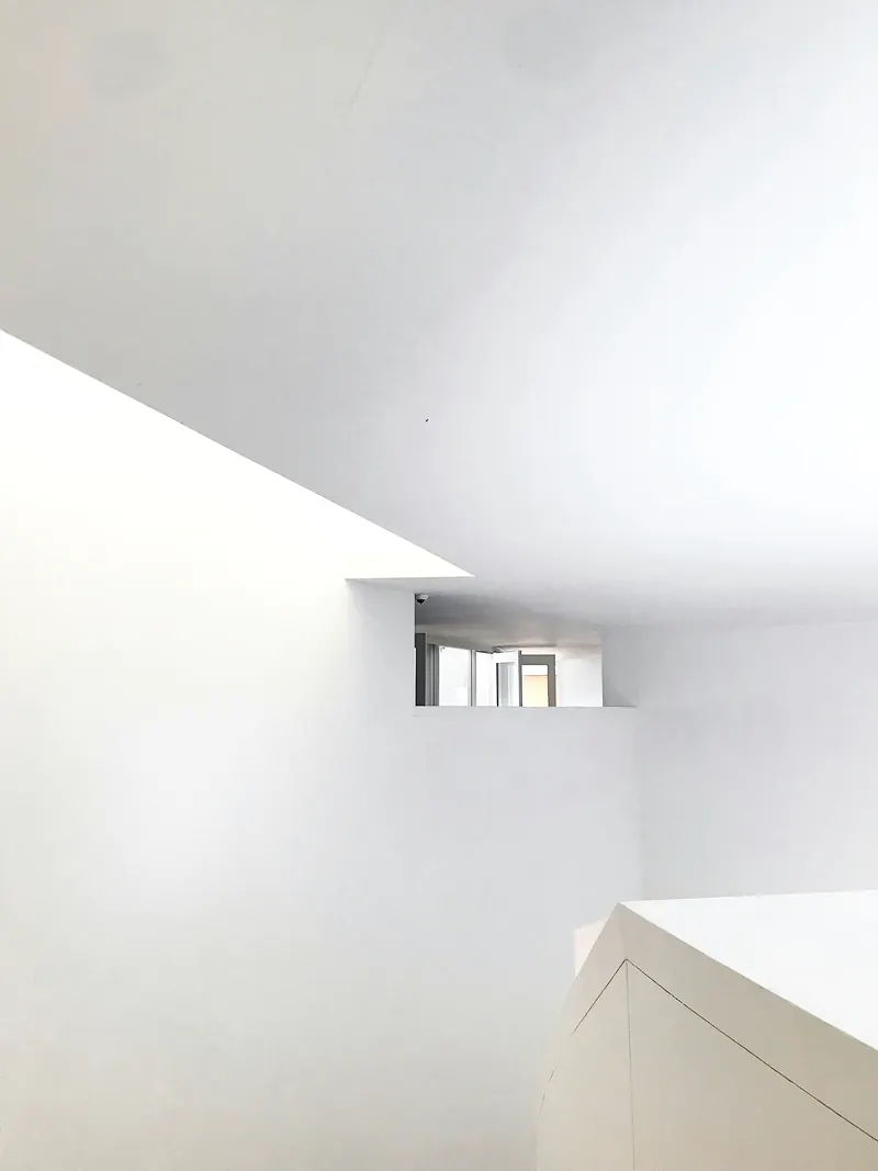 Angles de murs et de plafond d'un blanc uni, surfaces parfaitement lisses sous une lumière douce