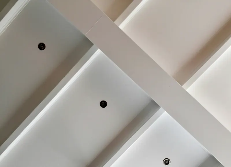 Plafond blanc à caissons, avec des petits spots encastrés dans chaque caisson