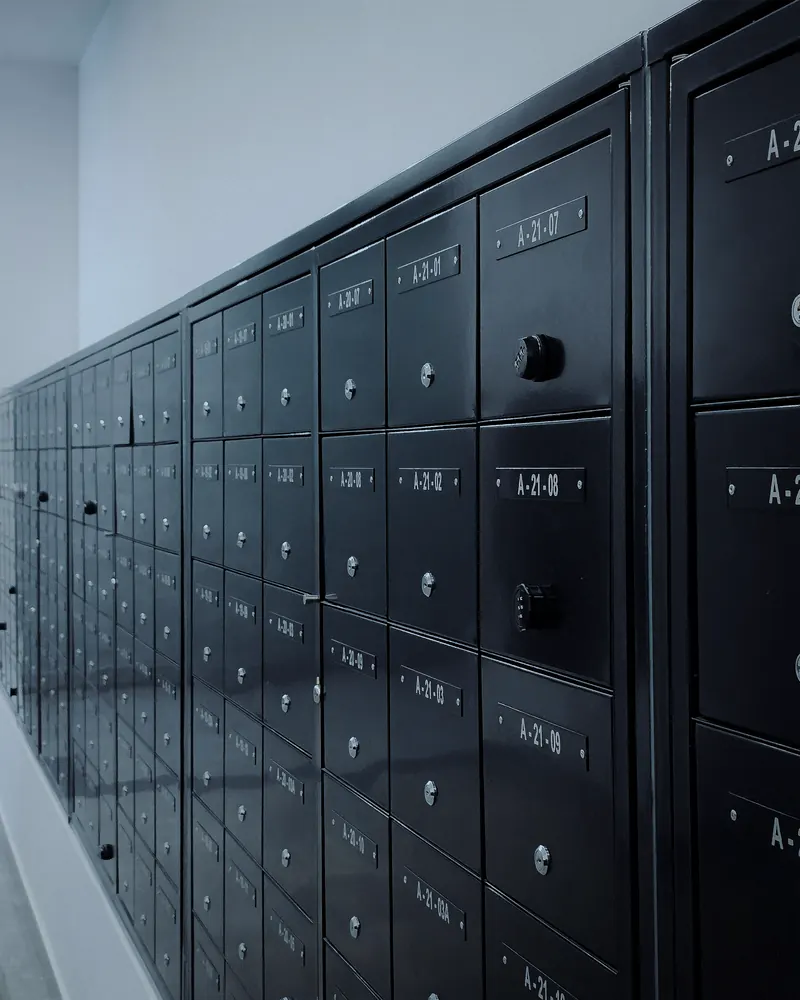 Rangée de boîtes aux lettres en métal sombre, numérotées, dans le hall d'un immeuble