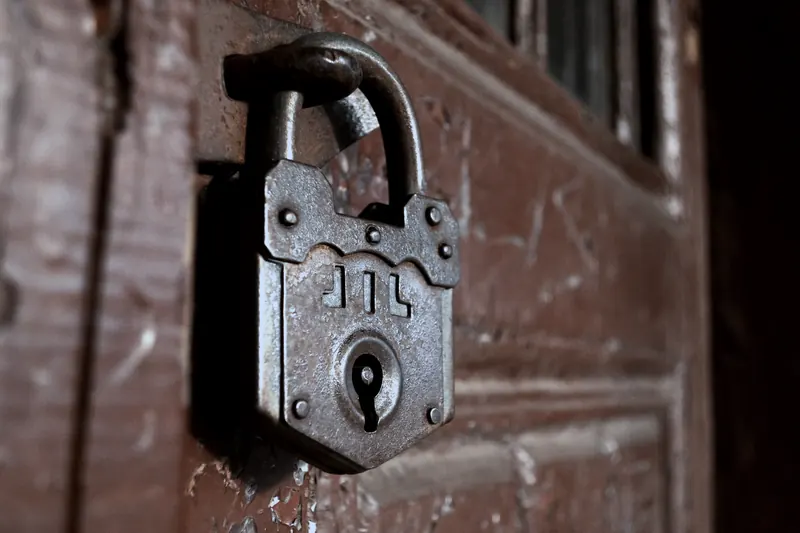 Vieux cadenas de fer rivé, fermé sur une porte en bois à la peinture écaillée
